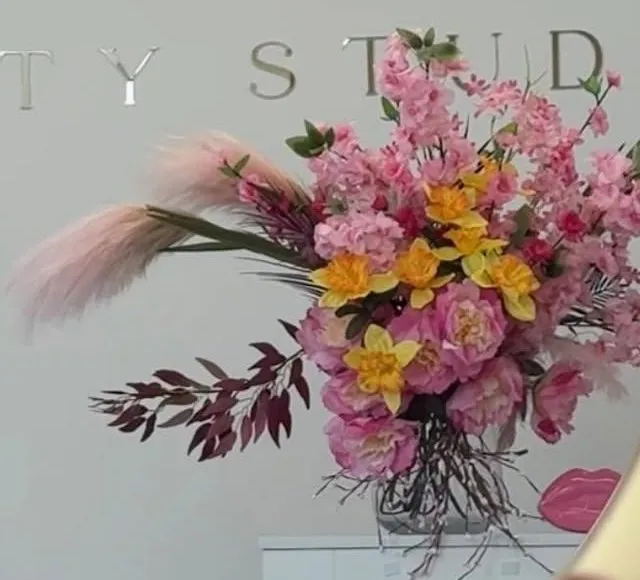 Rozā ziedu kompozīcija pie SHE beauty studio sienas